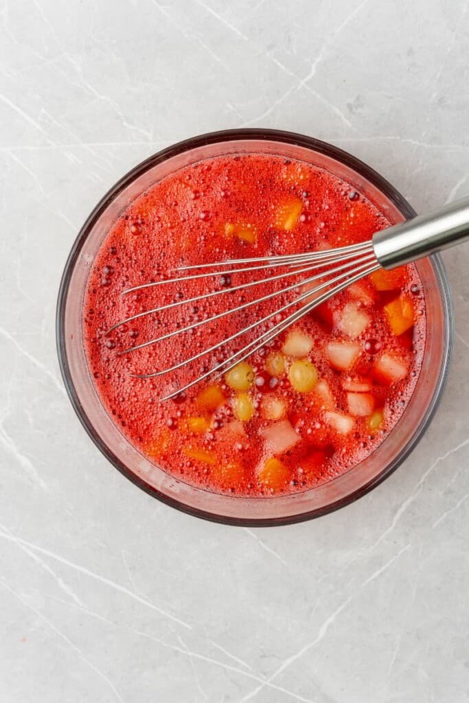 mixing together fruit cocktail and jello mix.
