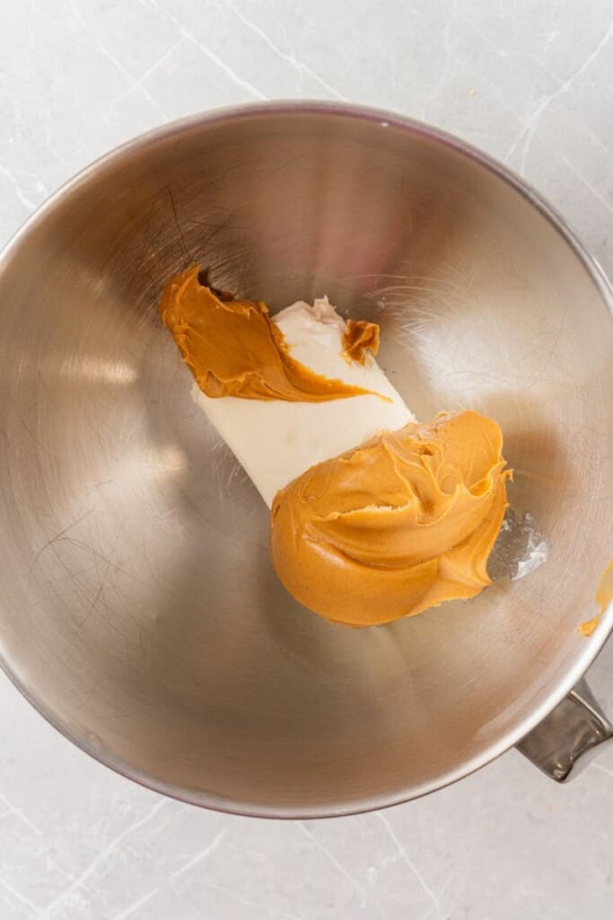 adding creamy peanut butter and cream cheese to a bowl.