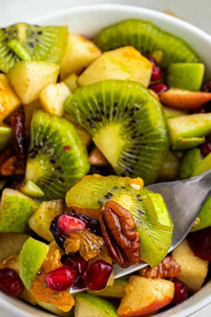 taking a bite out of kiwi and apple salad with a fork.
