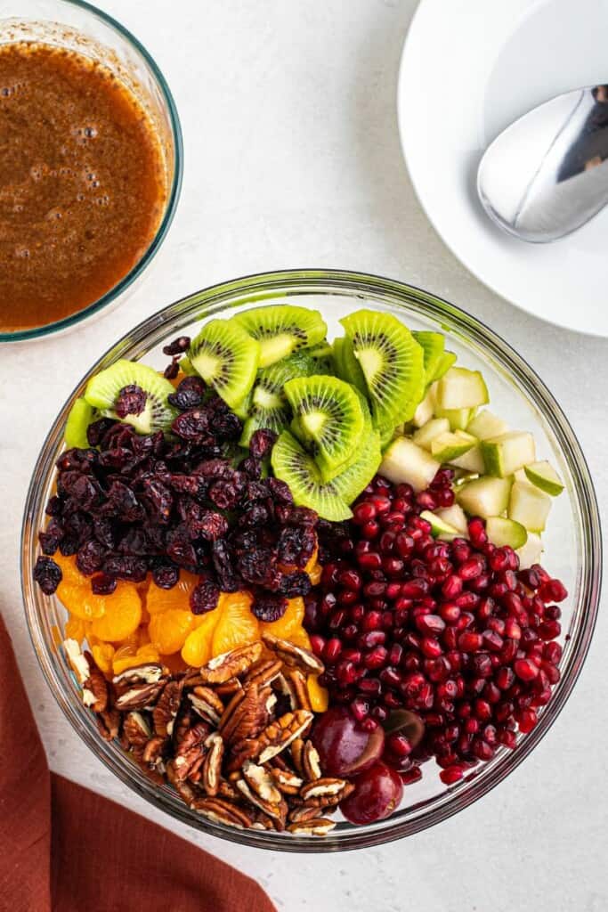 mixing chopped fruit with pecans and pomegranate seeds.