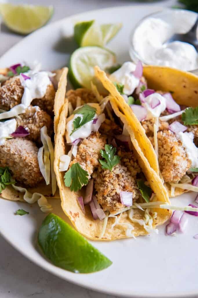 serving air fryer fish tacos in a corn tortilla with toppings.