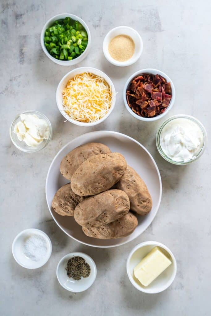 Ingredients needed to make double baked mashed potatoes: potatoes, cheddar cheese, sour cream, cream cheese, garlic powder, salt, pepper, bacon, and green onions.