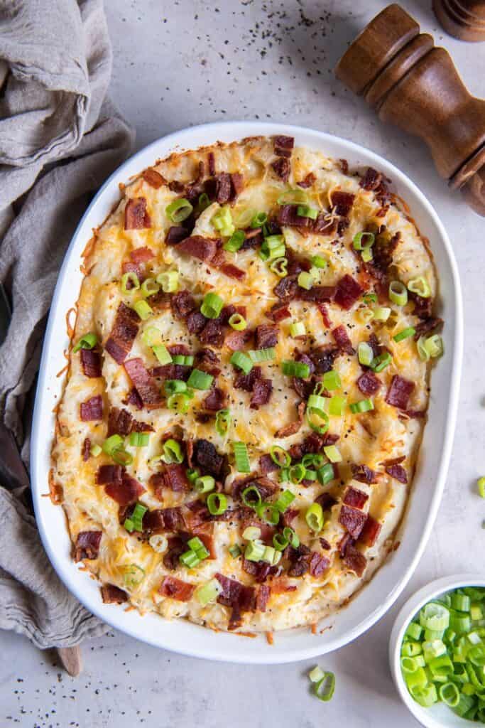 Finished twice baked mashed potatoes in a casserole dish topped with bacon and green onions.