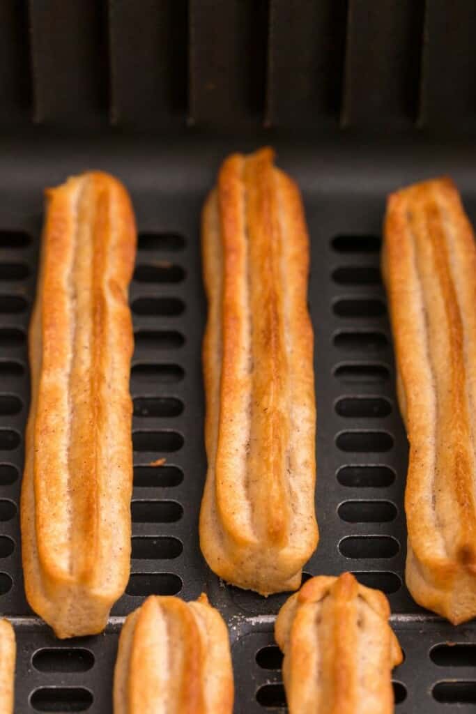 close up of baked cinnamon churros in air fryer basket