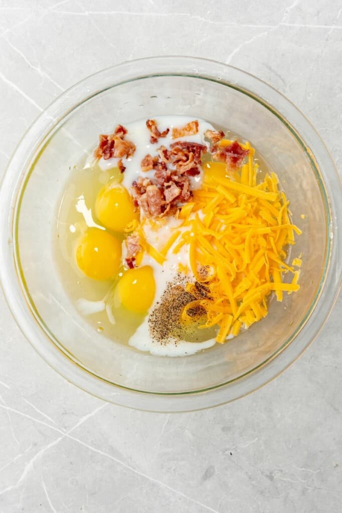 adding all of the ingredients needed to make egg bites into a glass bowl