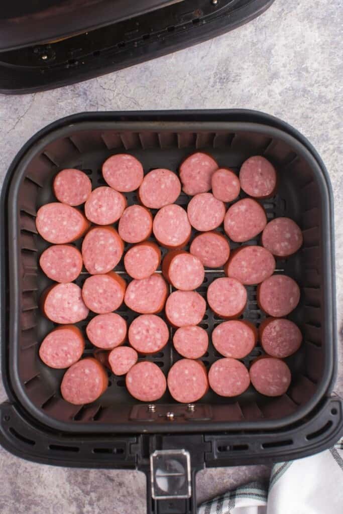 adding sliced kielbasa to air fryer basket