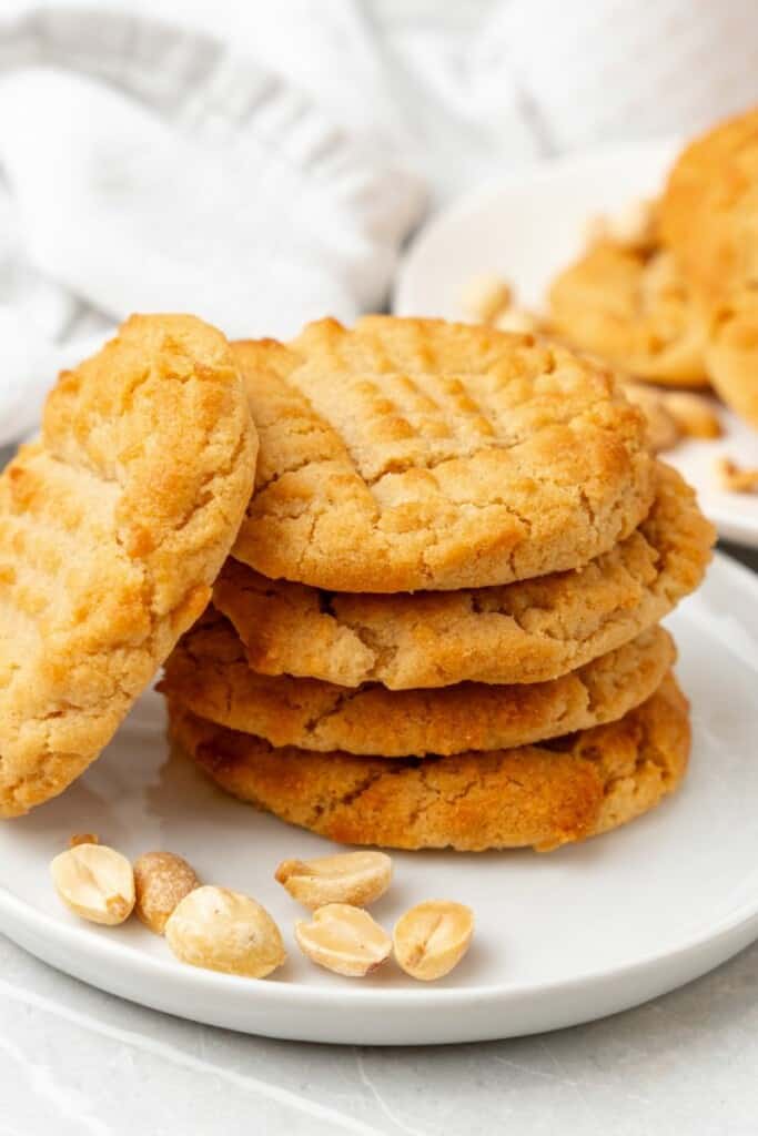 stacked peanut butter cookies on a white plate.