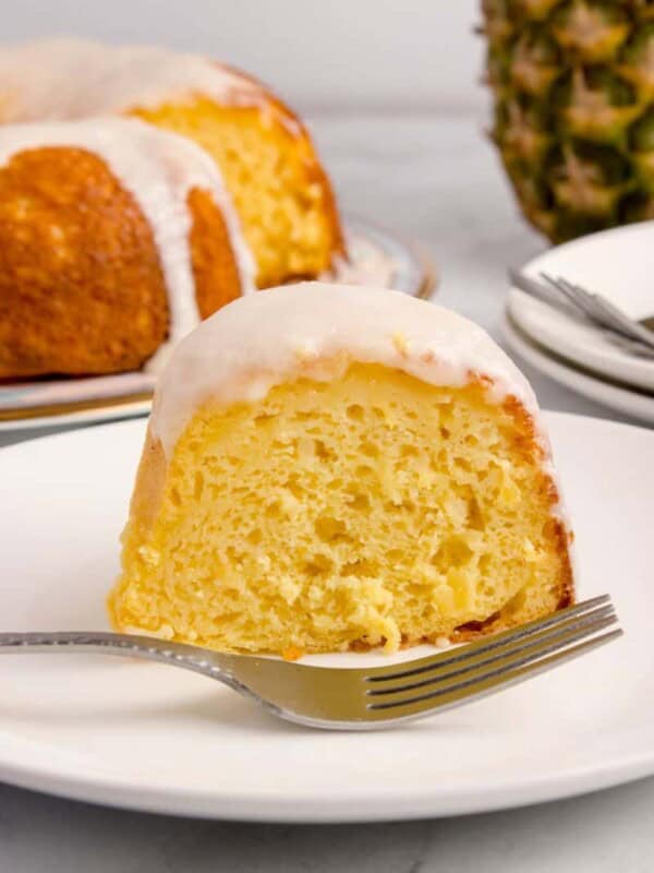 slicing pineapple bundt cake on a plate