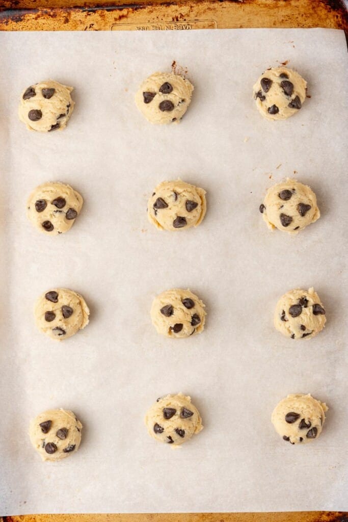 adding eggless cookie dough balls to baking sheet
