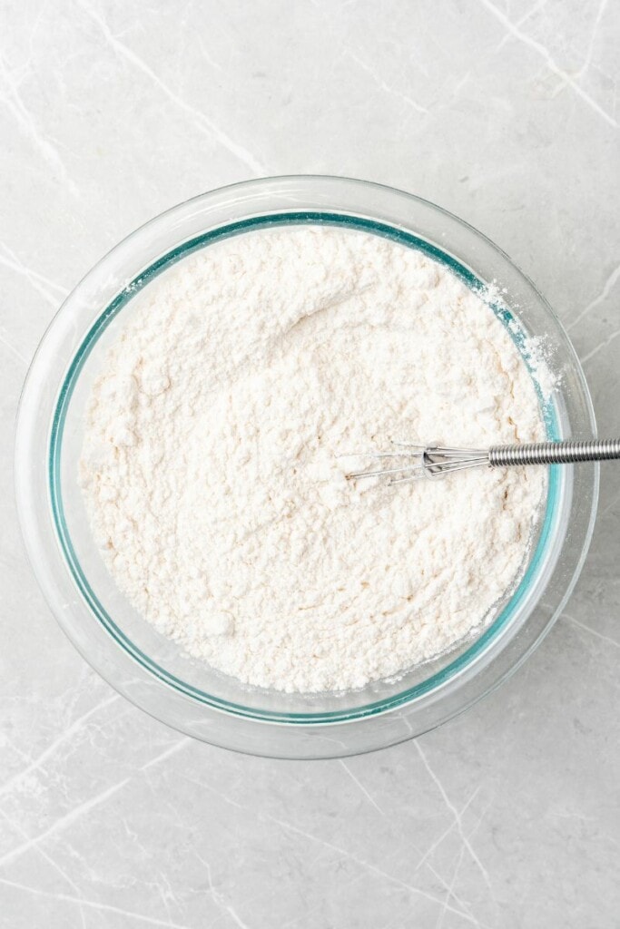 mixing together flour and baking powder in a glass bowl