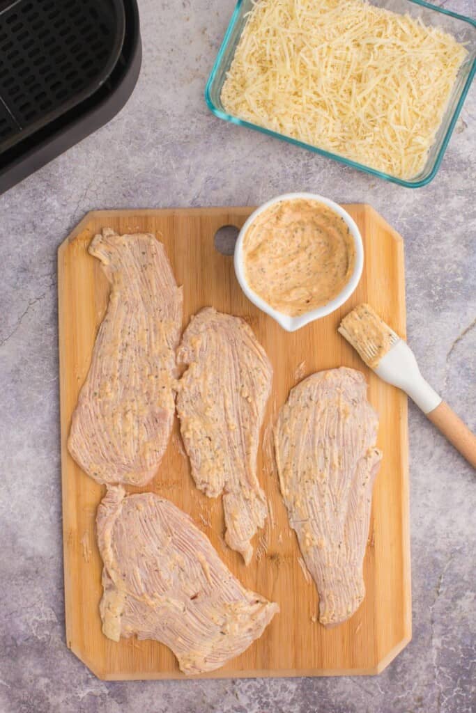 brushing spiced mayo onto chicken breast