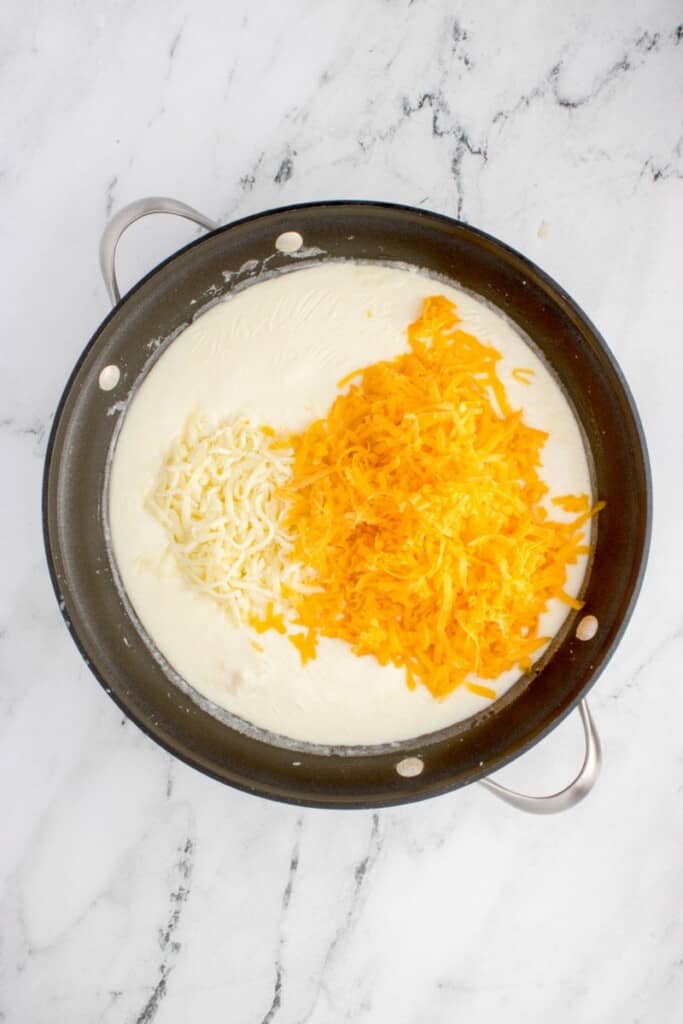 adding heavy cream and cheese to roux in hot pan