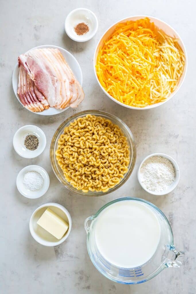 Ingredients needed to make bacon mac and cheese: elbow noodles, bacon, butter, flour, milk, salt, pepper, nutmeg, cheddar cheese, and gruyere cheese.