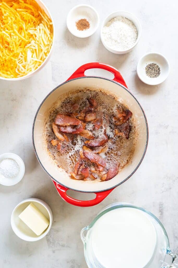 Bacon being cooked in a dutch oven pot to make mac and bacon cheese.