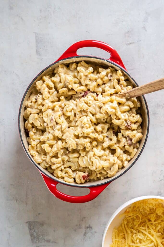 Dutch oven mac and cheese in a pot before being placed in the oven with more cheese.