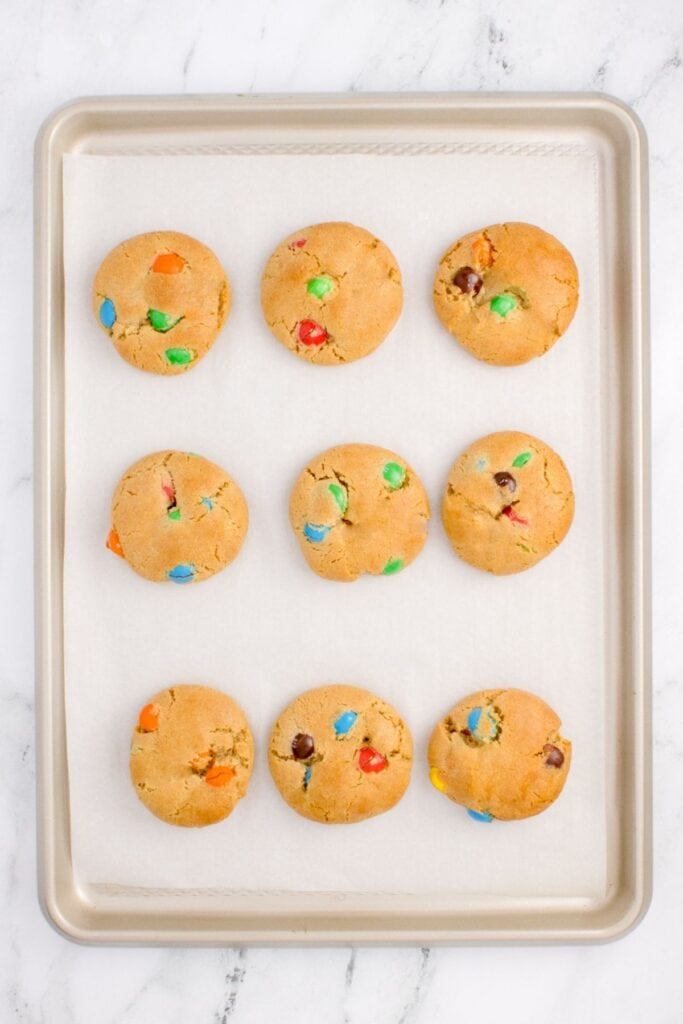 Baked M&M cookie recipe on a cookie sheet.