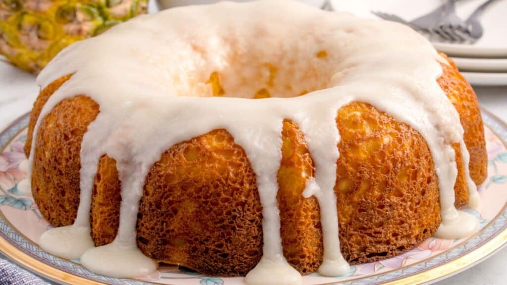 Full view of the pineapple cream cheese pound cake with pineapple glaze dripping on the sides of it.