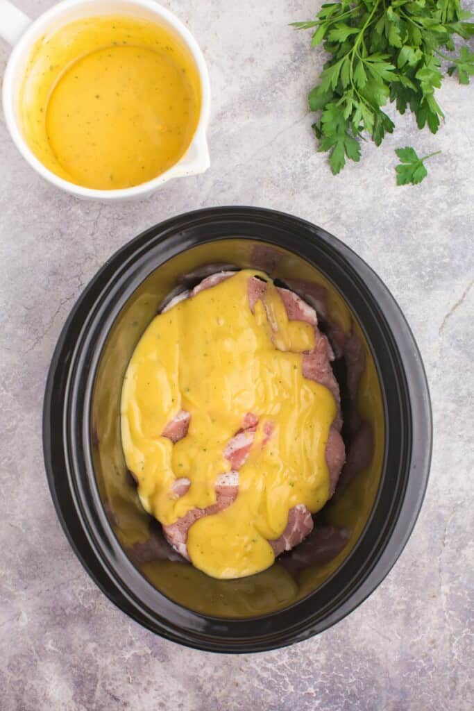 Pouring cream of chicken soup over boneless pork fillets.