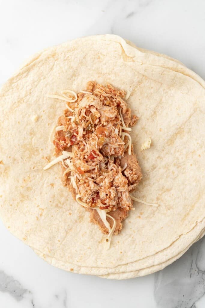 Chicken filling added added on top of beans and cheese in center of tortilla.