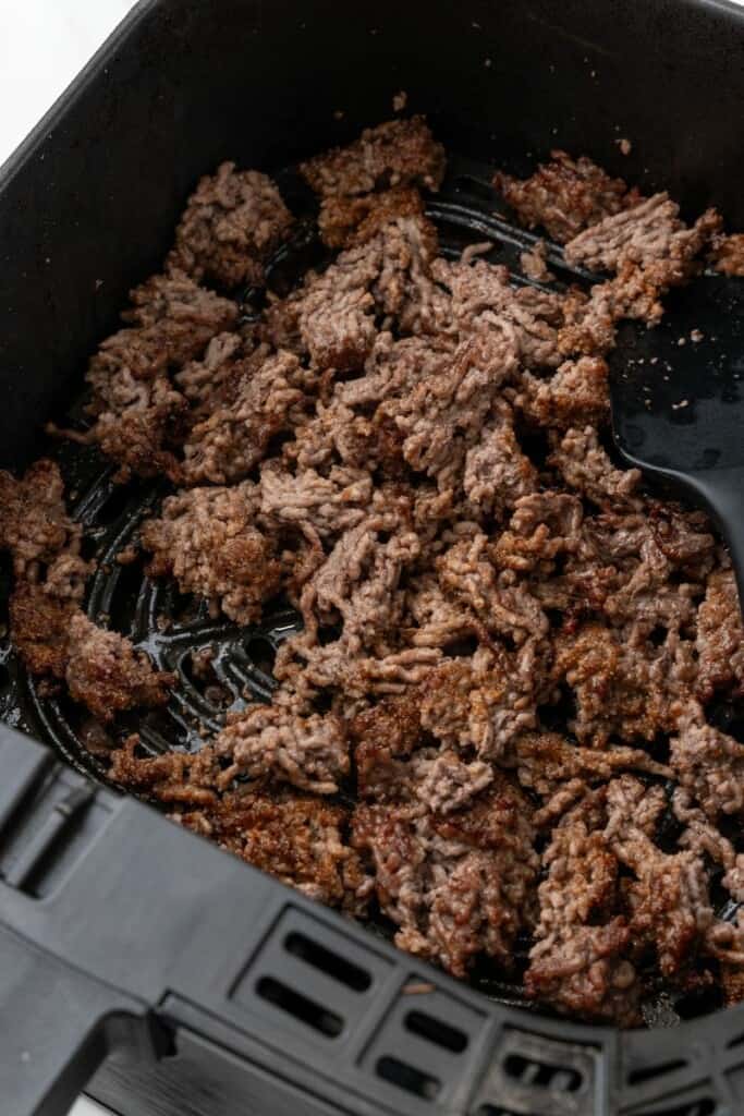 Broken up, browned meat in air fryer basket.