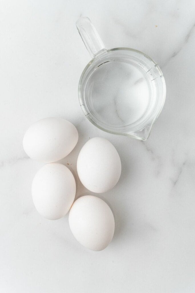 4 eggs next to a measuring cup.