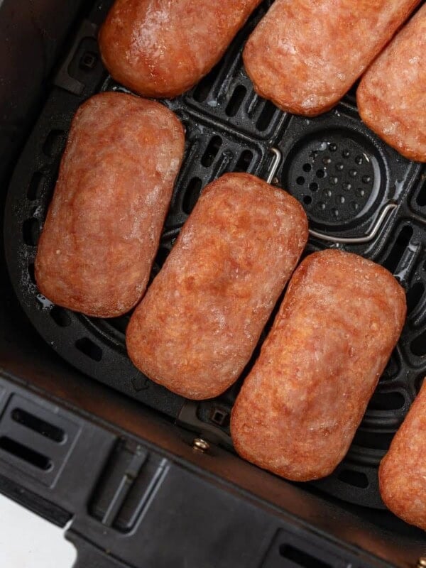 Close up of slices of spam in an air fryer.