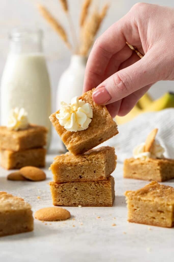 Picking up a frosted banana blondie from a small stack.