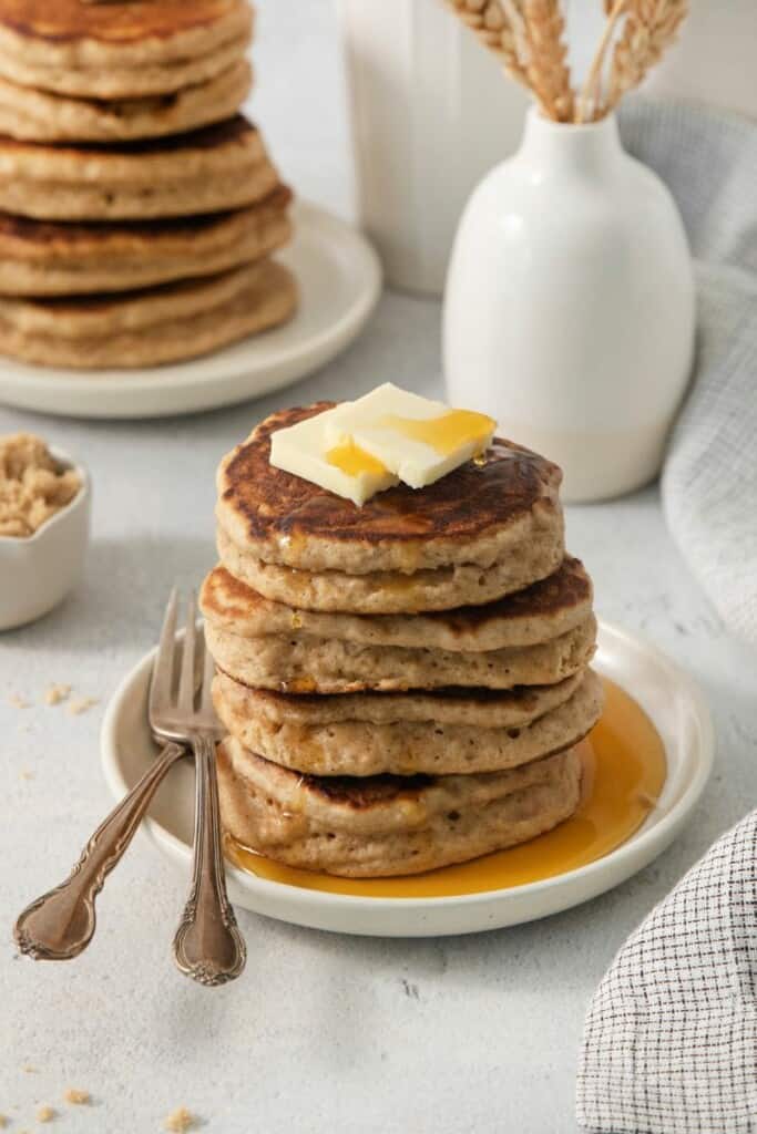 4 brown sugar pancakes on a plate, covered with syrup.