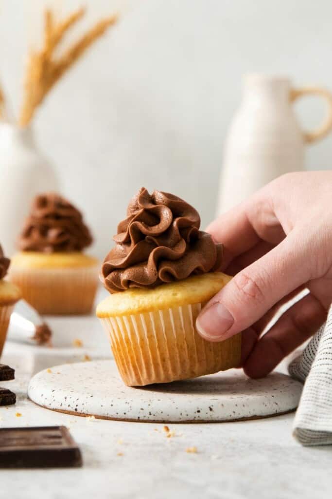 Picking up a cupcake with chocolate cream cheese frosting.