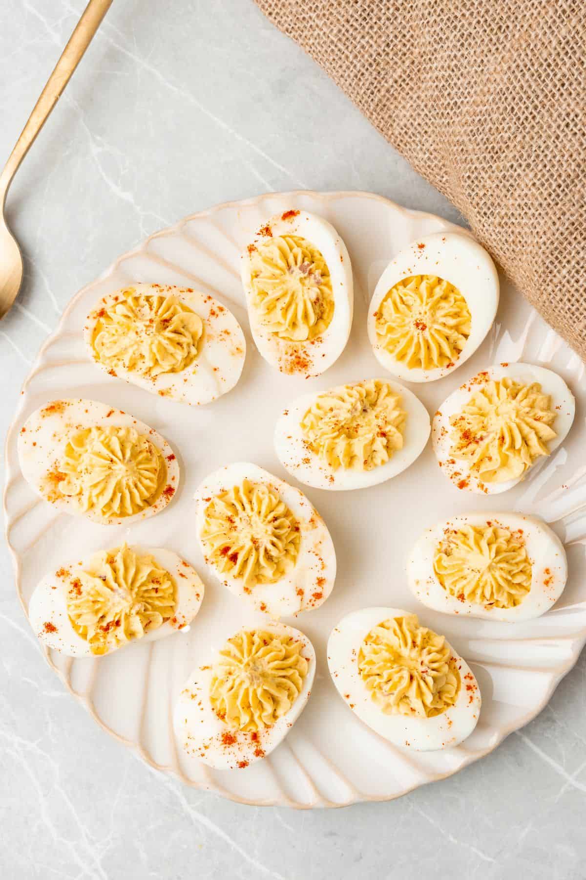 Million dollar deviled eggs on a round white serving platter.