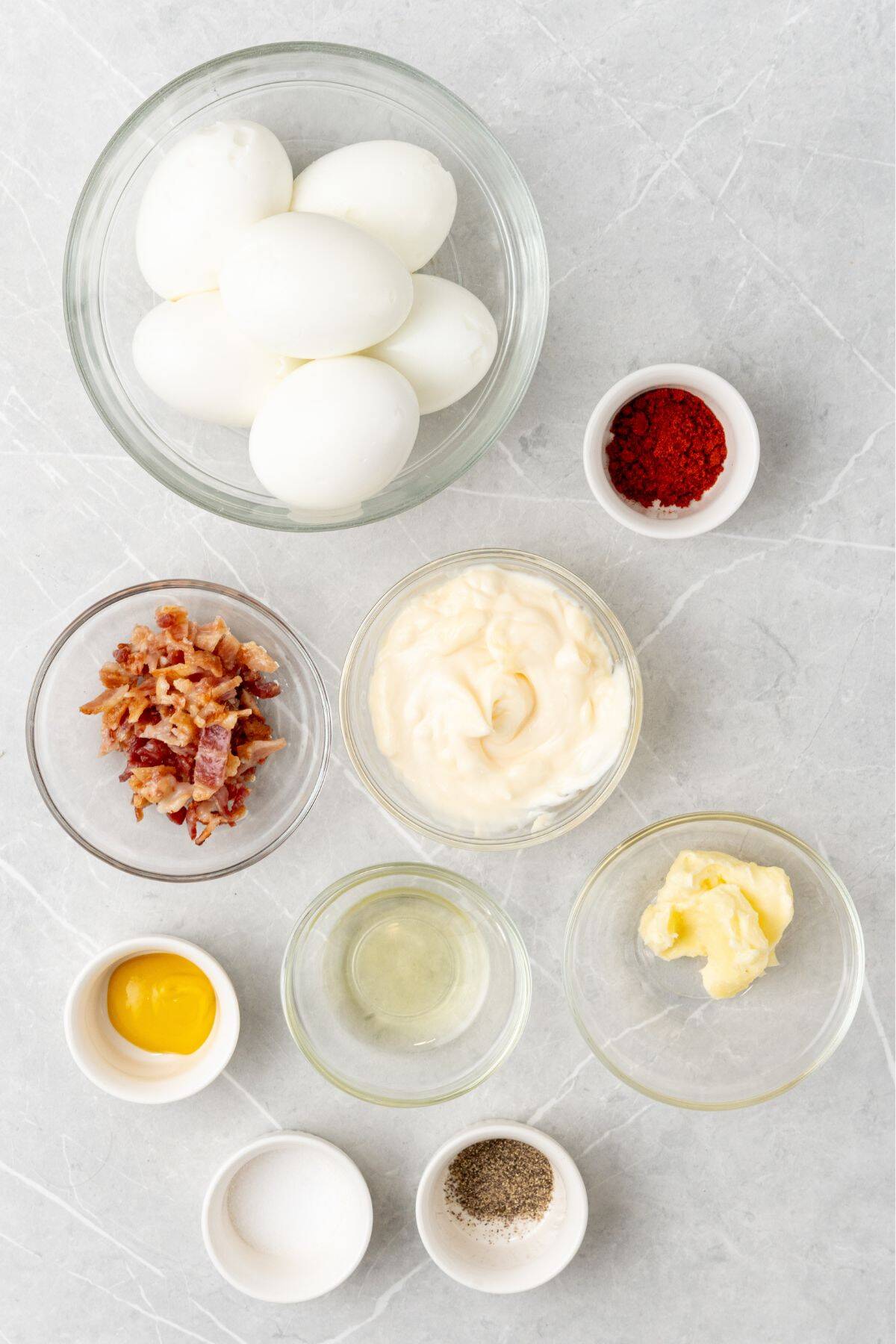 Ingredients needed to make million dollar deviled eggs: hard boiled eggs, mayo, pickle juice, bacon, butter, mustard, salt, pepper, and paprika.