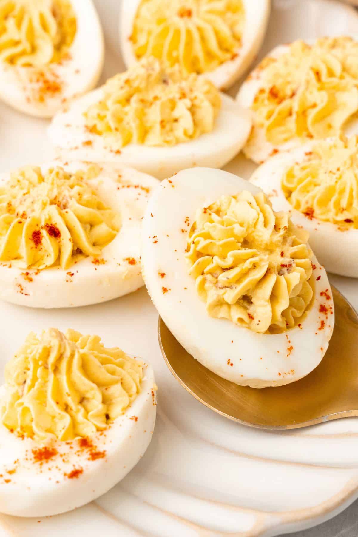 Very close up of the million dollar deviled eggs with a spoon picking one up.