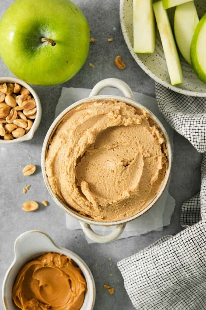 honey cinnamon fruit dip in a white bowl with nuts and sliced fruit.