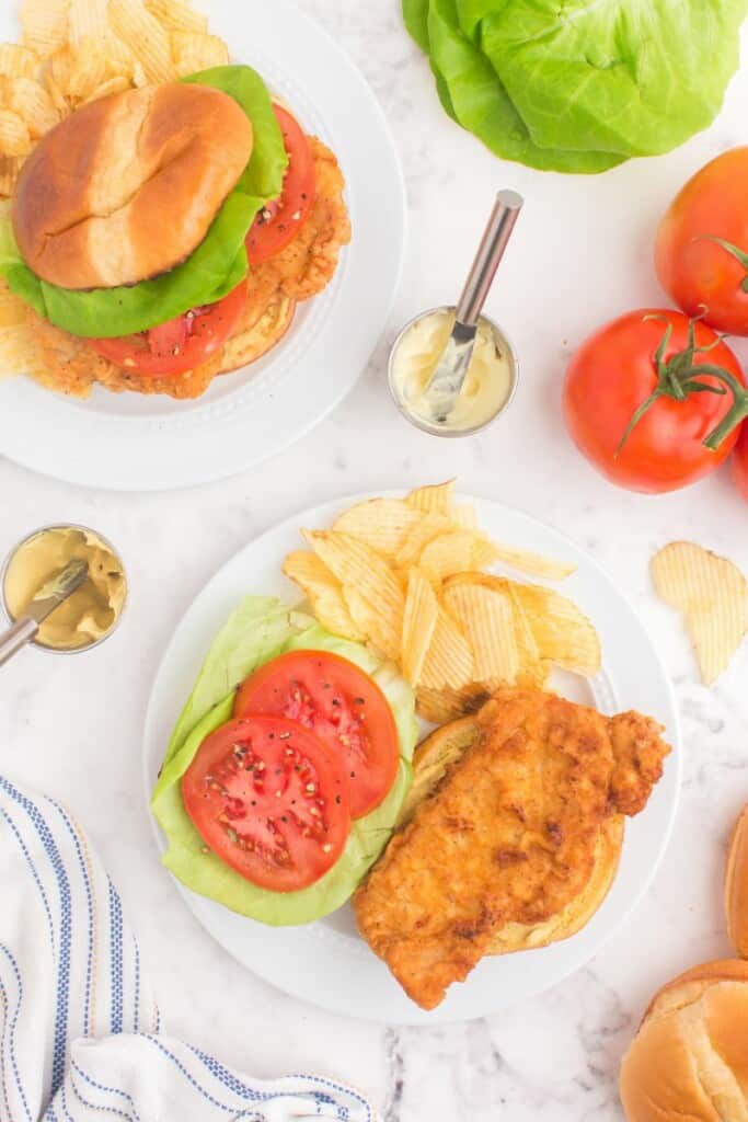 Crispy pork chop on brioche bun with lettuce and tomato - served with potato chips.