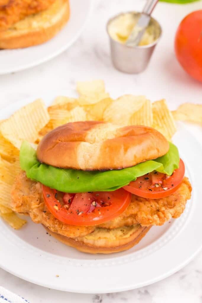 Fried pork chop sandwich with lettuce and tomato.