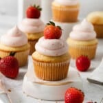 Vanilla cupcakes with homemade strawberry frosting and a fresh berry on top.