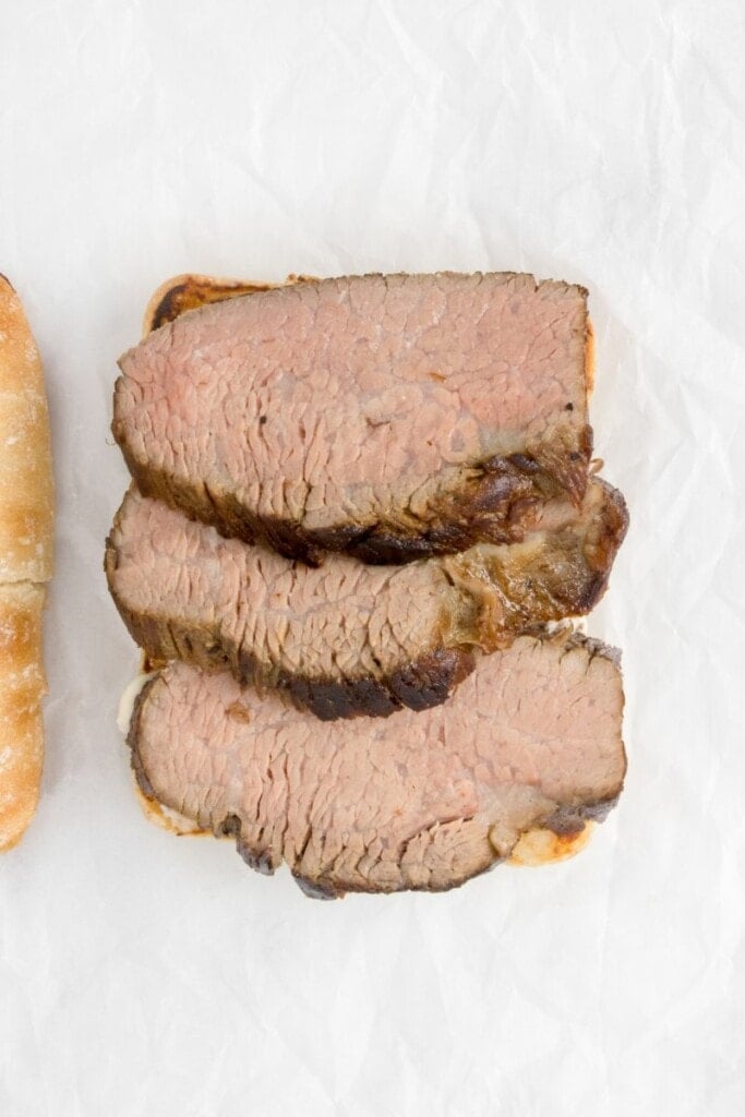 Slices of tri tip beef onto sliced bread.