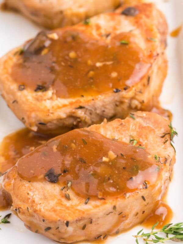 Instant pot pork chops close up on a white plate covered with the gravy from the pot.