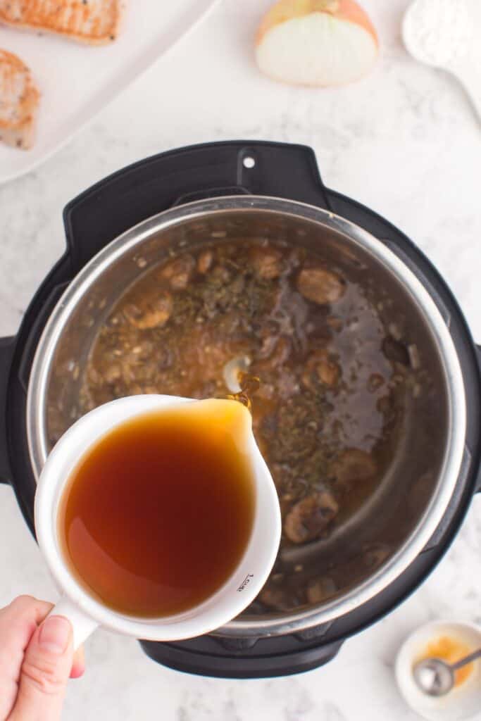 Pouring the beef broth into the Instant Pot to complete the pork chop sauce.