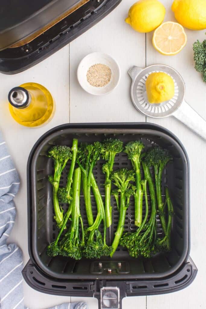raw broccolini stalks in air fryer basket