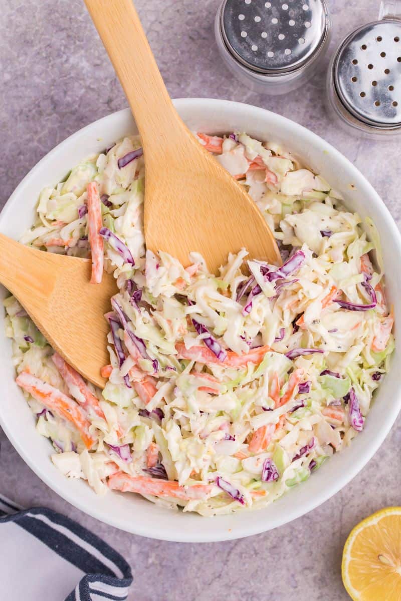 tossing coleslaw with two wooden salad tongs