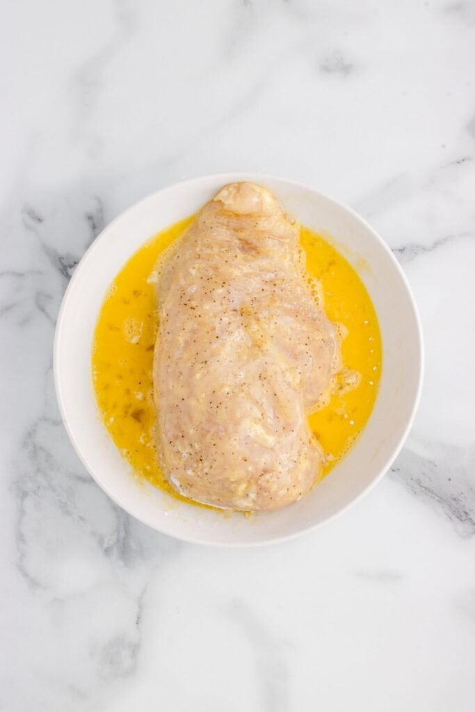 dipping flour coated chicken into egg wash