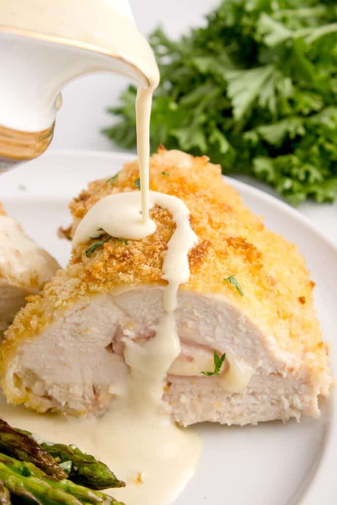 drizzling creamy dijon sauce over the stuffed chicken