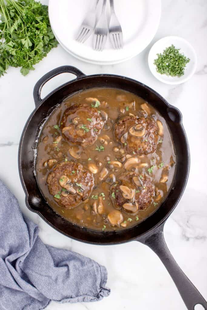 simmered homemade salisbury steak in a cast iron skillet