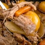 Close up of the sirloin tip roast in the crock pot being picked up with a spoon with carrots and baby potatoes.