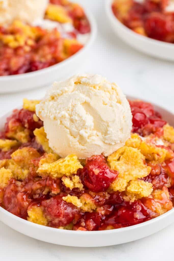 serving homemade cherry dump cake with a scoop of vanilla ice cream