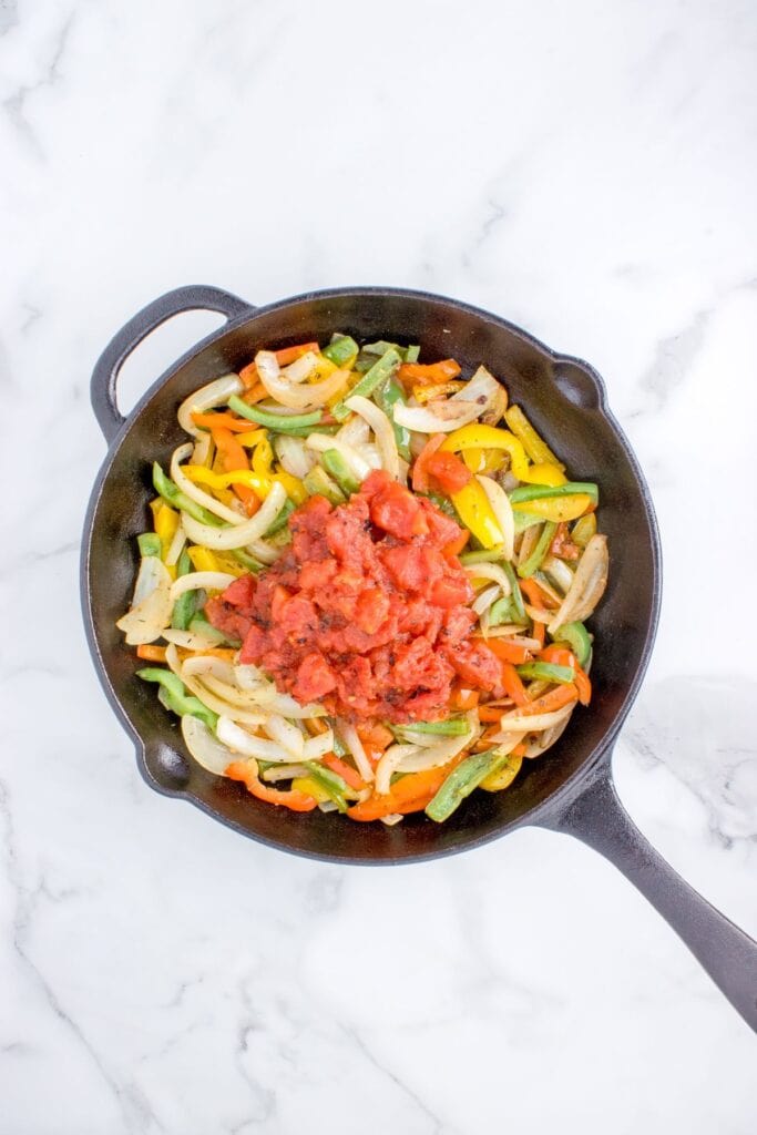 adding roasted tomatoes to sauteed veggies in pan