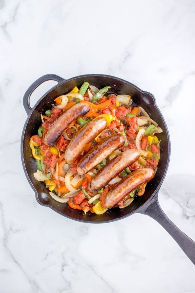 adding seared italian sausages back to the peppers and onions