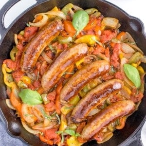 overhead shot of italian sausage, peppers and onions in a cast iron skillet