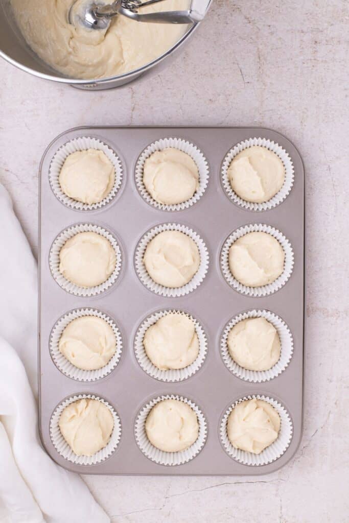 filling cupcake lines with batter by a scooper